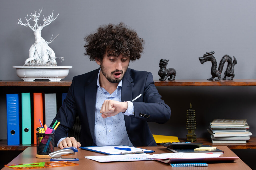 front-view-young-businessman-sitting-desk-checking-time