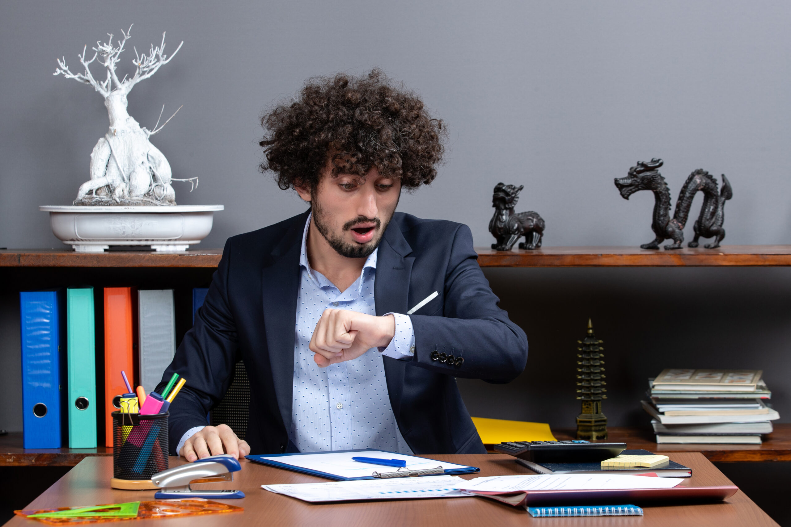 front-view-young-businessman-sitting-desk-checking-time