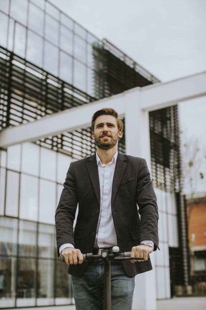 Young business man in a casual clothes riding an electric scoote